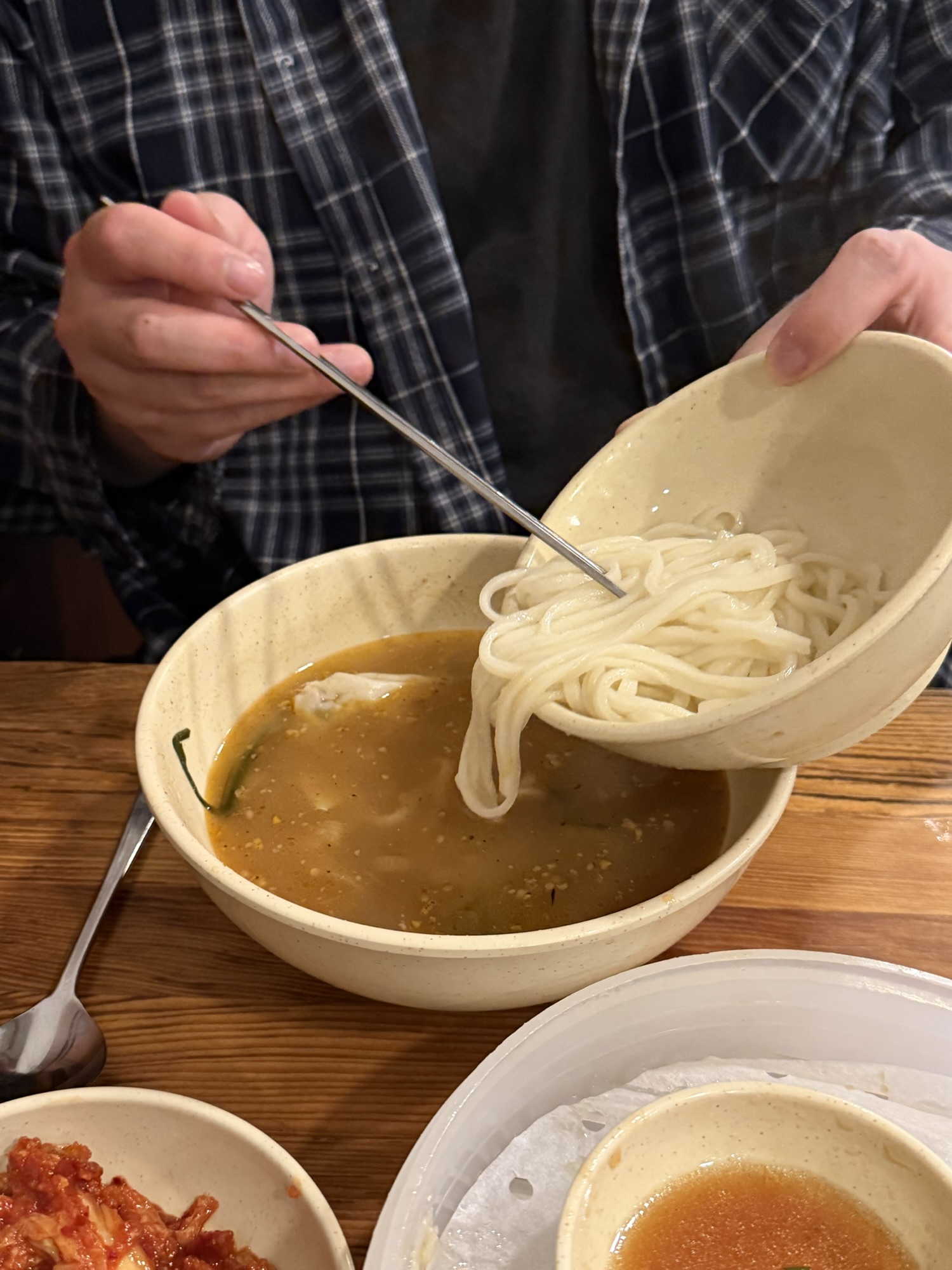 Pouring extra noodles (sari) into the leftover kalguksu broth at Myeongdong Kyoja