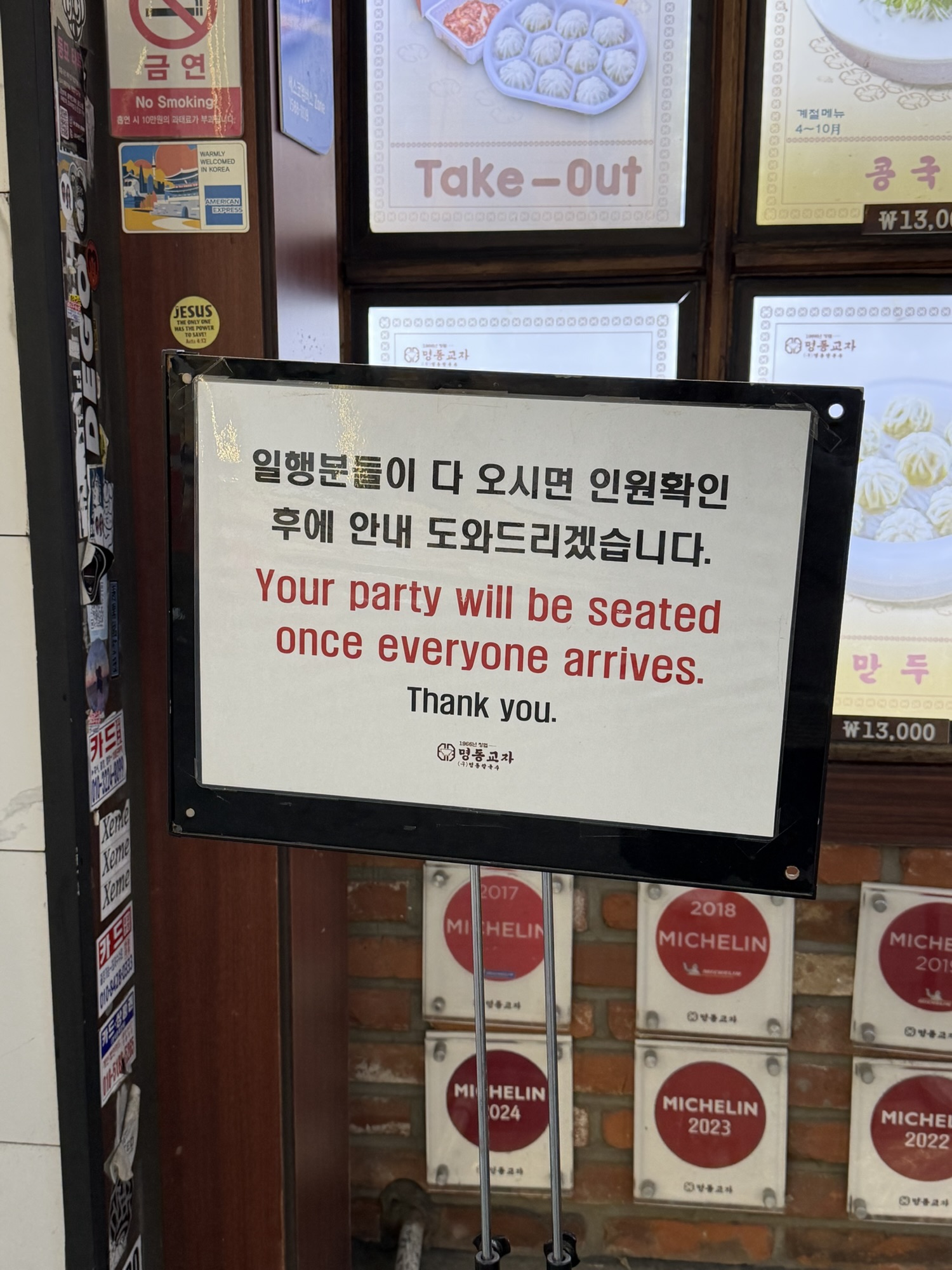 Sign at Myeongdong Kyoja entrance: Your party will be seated once everyone arrives, with Michelin Guide plaques visible