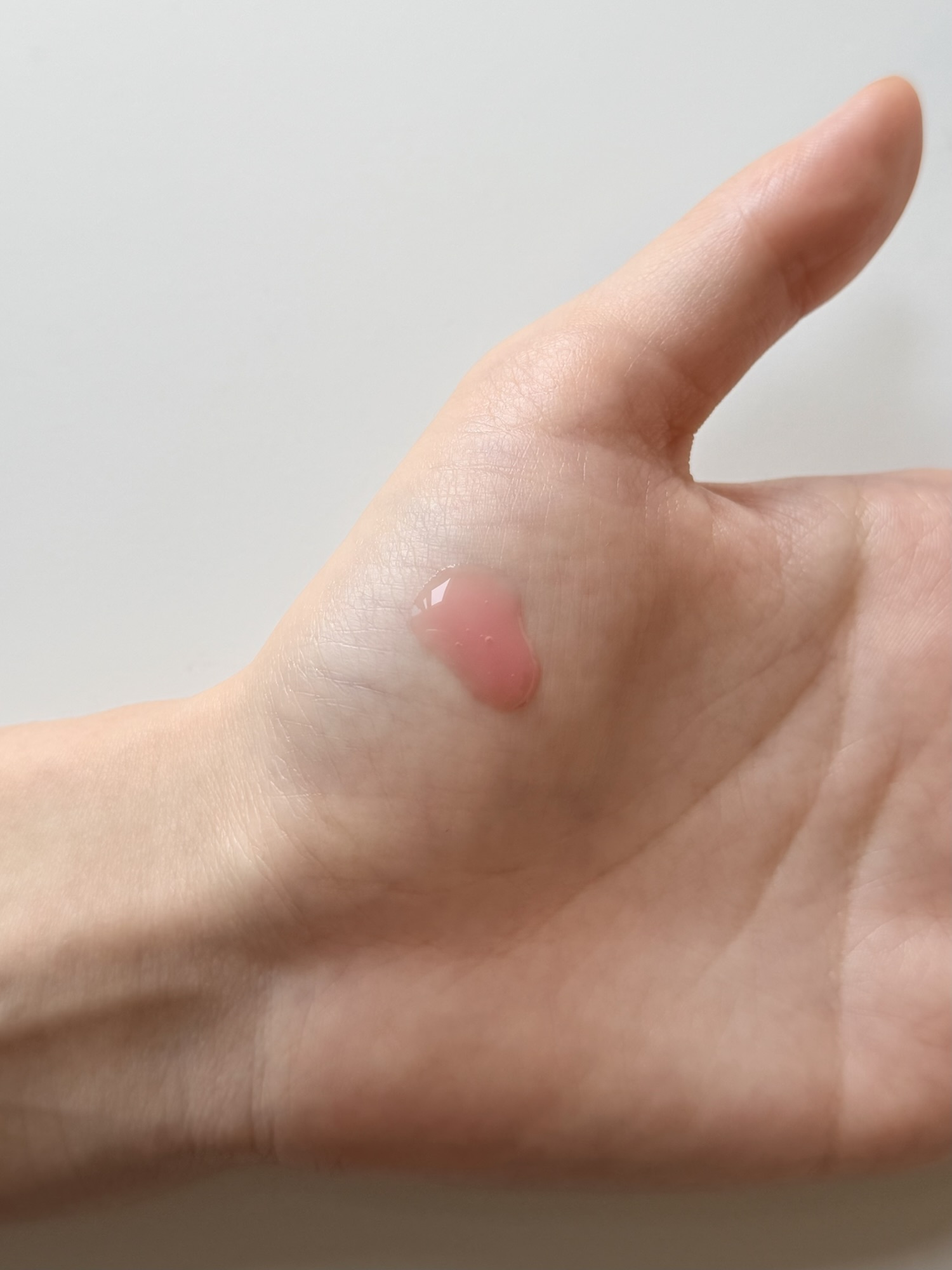 Medicube PDRN Pink Peptide Serum showing the runny watery texture as it spreads from a single drop on the back of a hand