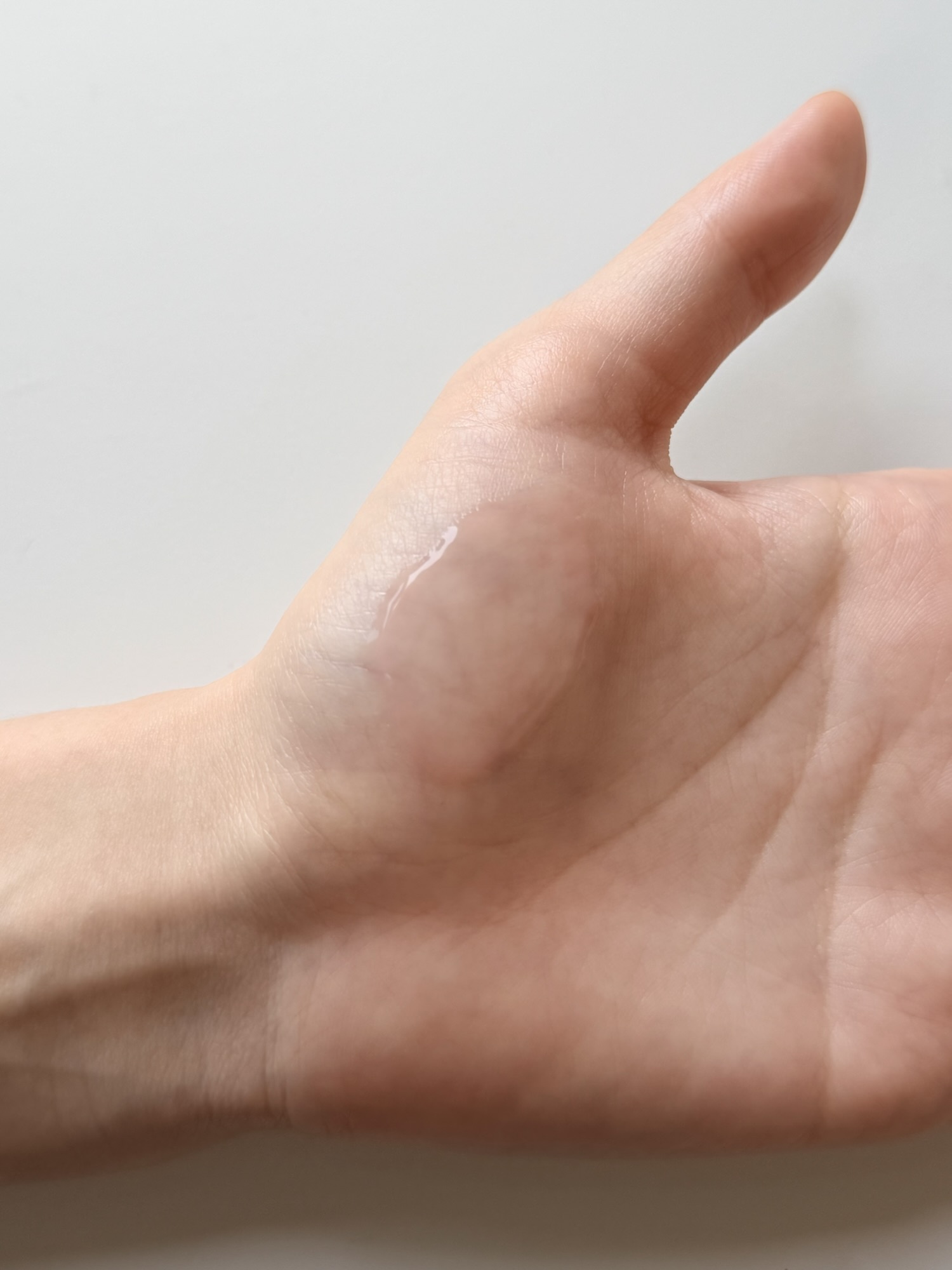 Medicube PDRN Pink Peptide Serum being spread across the back of a hand demonstrating the easy glide and good spreadability mid-application