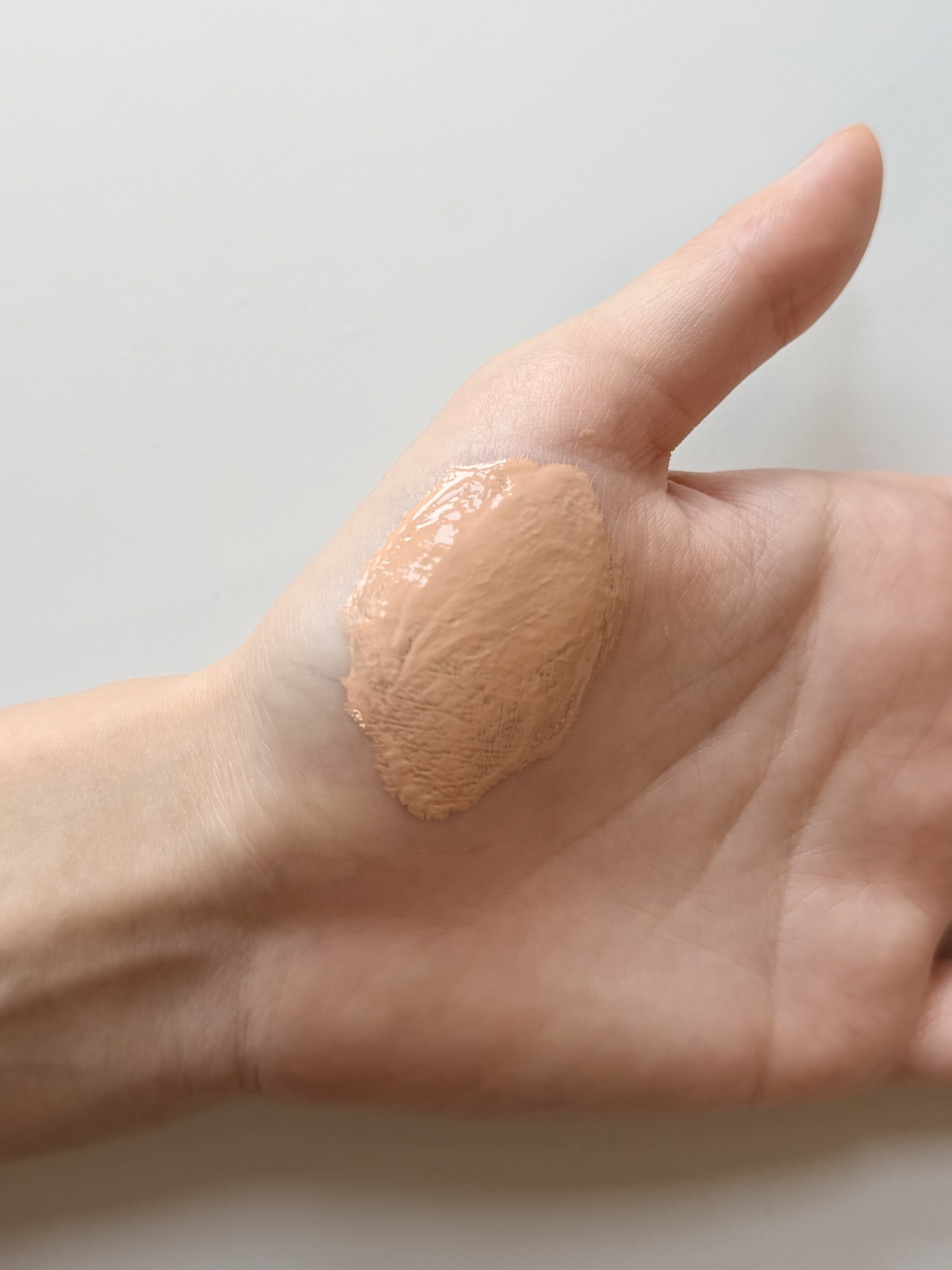 Foundation and Medicube PDRN serum being blended together on the back of a hand showing dewy absorption mid-application
