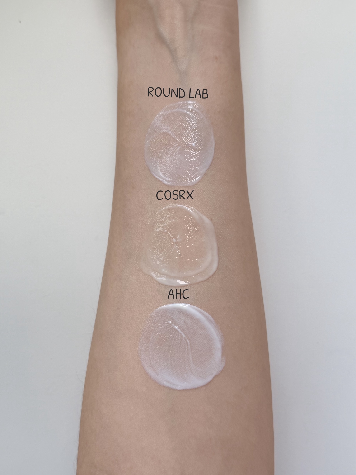 ROUND LAB vs COSRX vs AHC sunscreen finish comparison on the back of hand — blended side by side