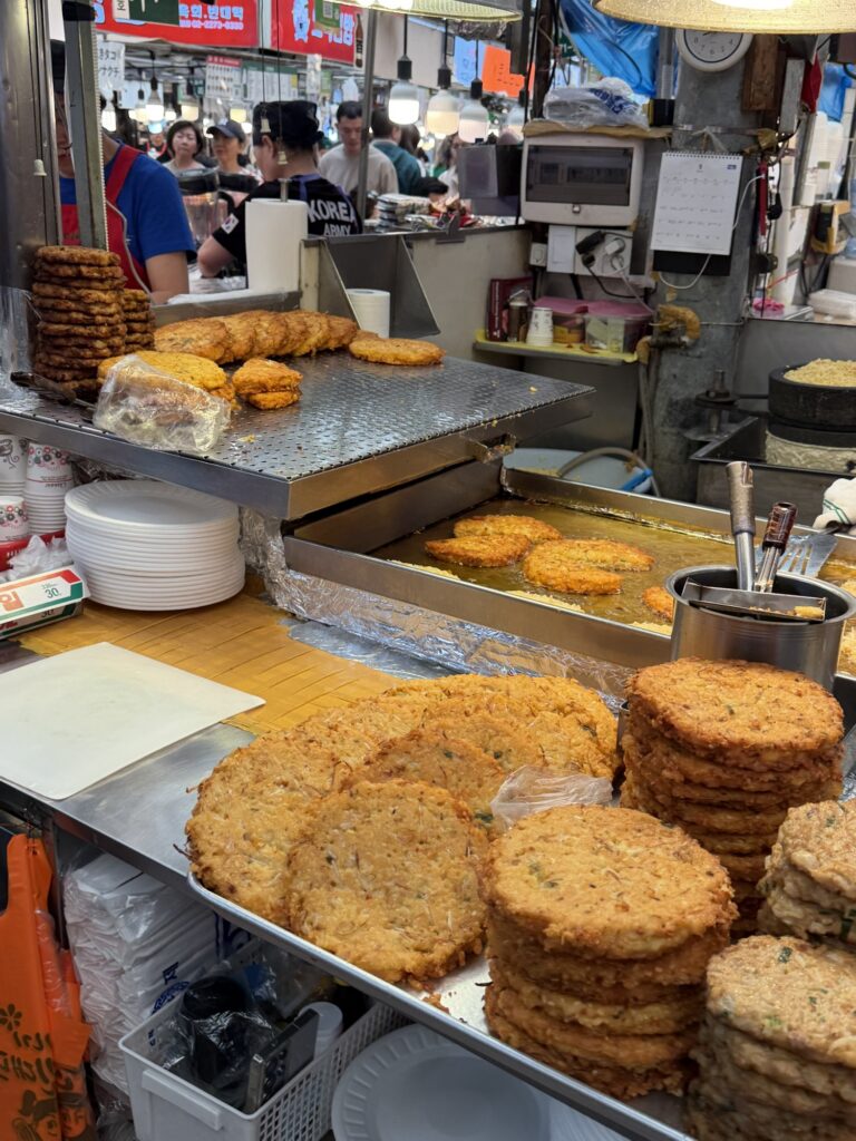 Stacks of golden-fried bindaetteok (mung bean pancakes) at a Gwangjang Market stall, the dish the market is most famous for