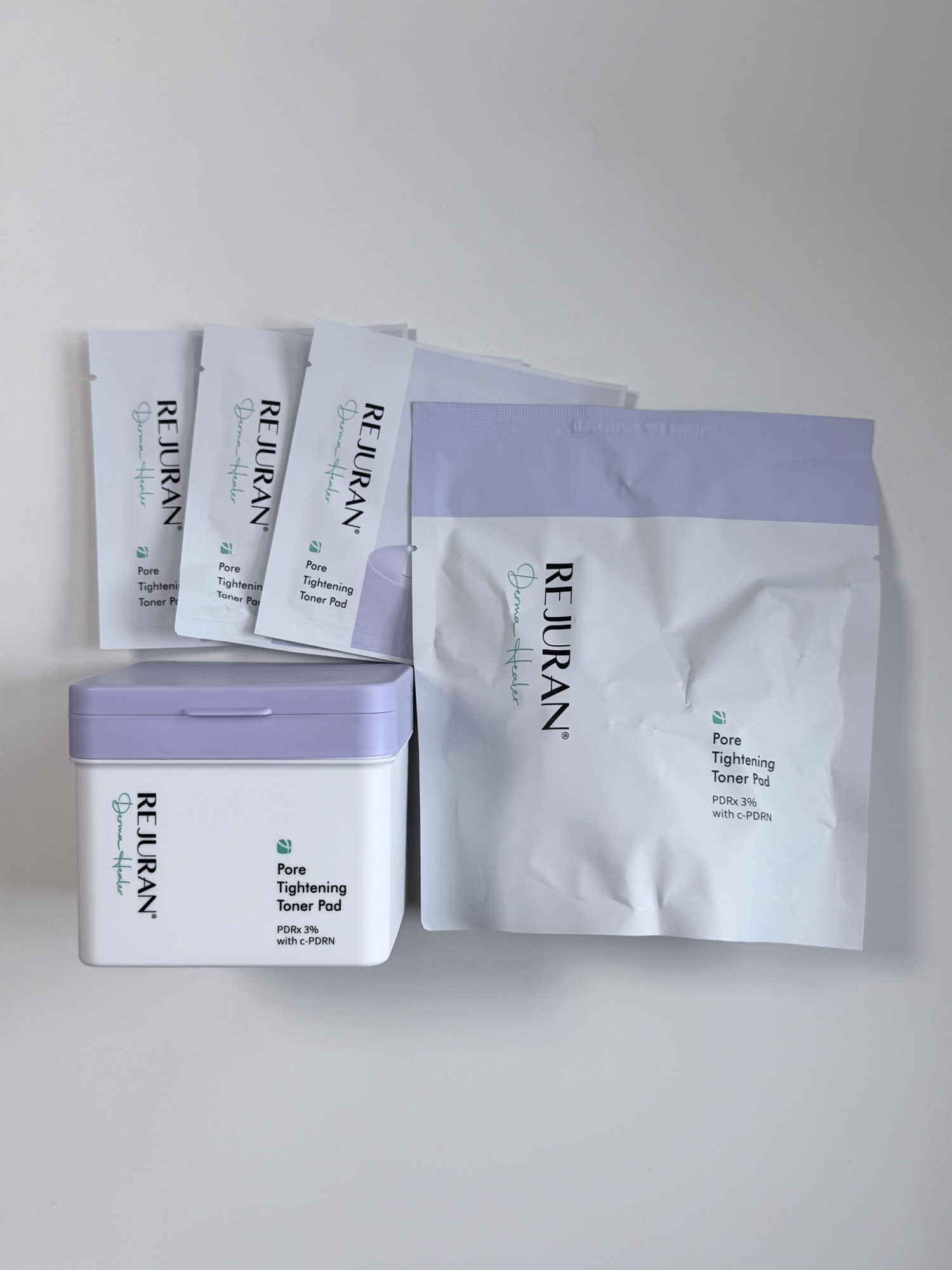 Rejuran Pore Tightening Toner Pad 126-pad set unboxed — main container, refill pouch, and three 2-pack travel sachets