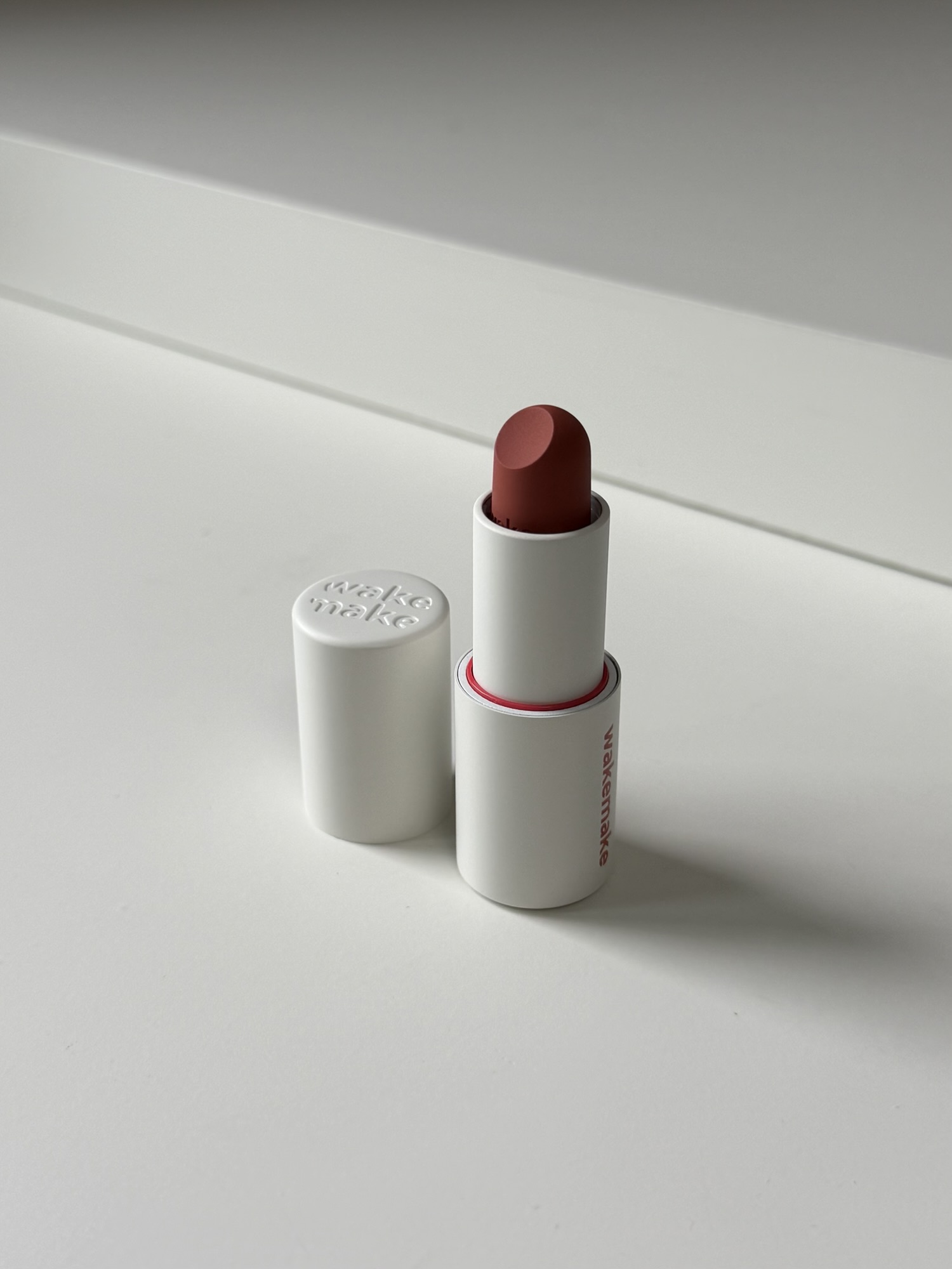 Wakemake Blurring Balm Stick #08 Maple Coral bullet close-up — matte coral-brown with wakemake emboss