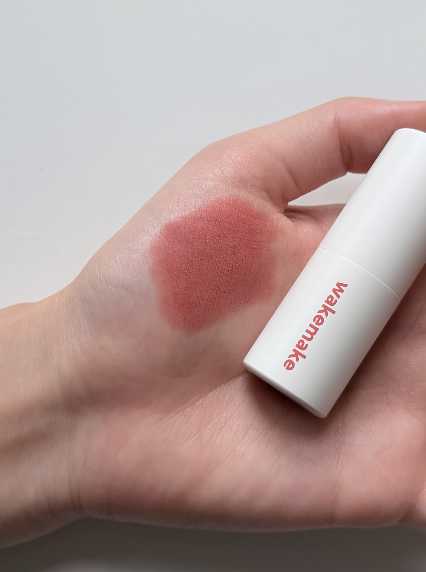 Wakemake Blurring Balm Stick #08 hand swatch — 2-3 layers built up: warm coral-terracotta, buildable without heaviness