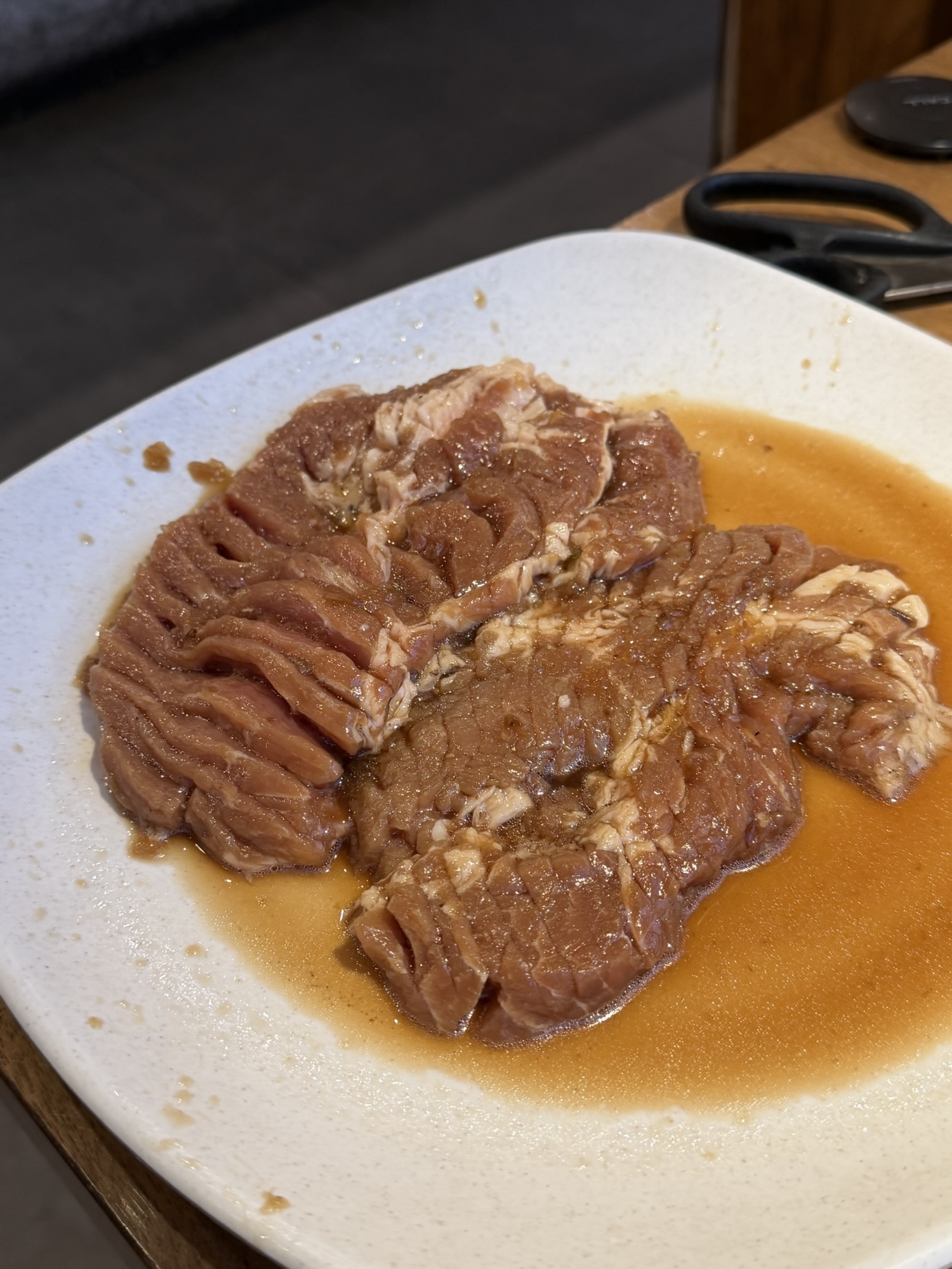 Raw marinated pork galbi at Songdo Galbi — two thick pieces per serving, scored all over so the marinade gets into every fold