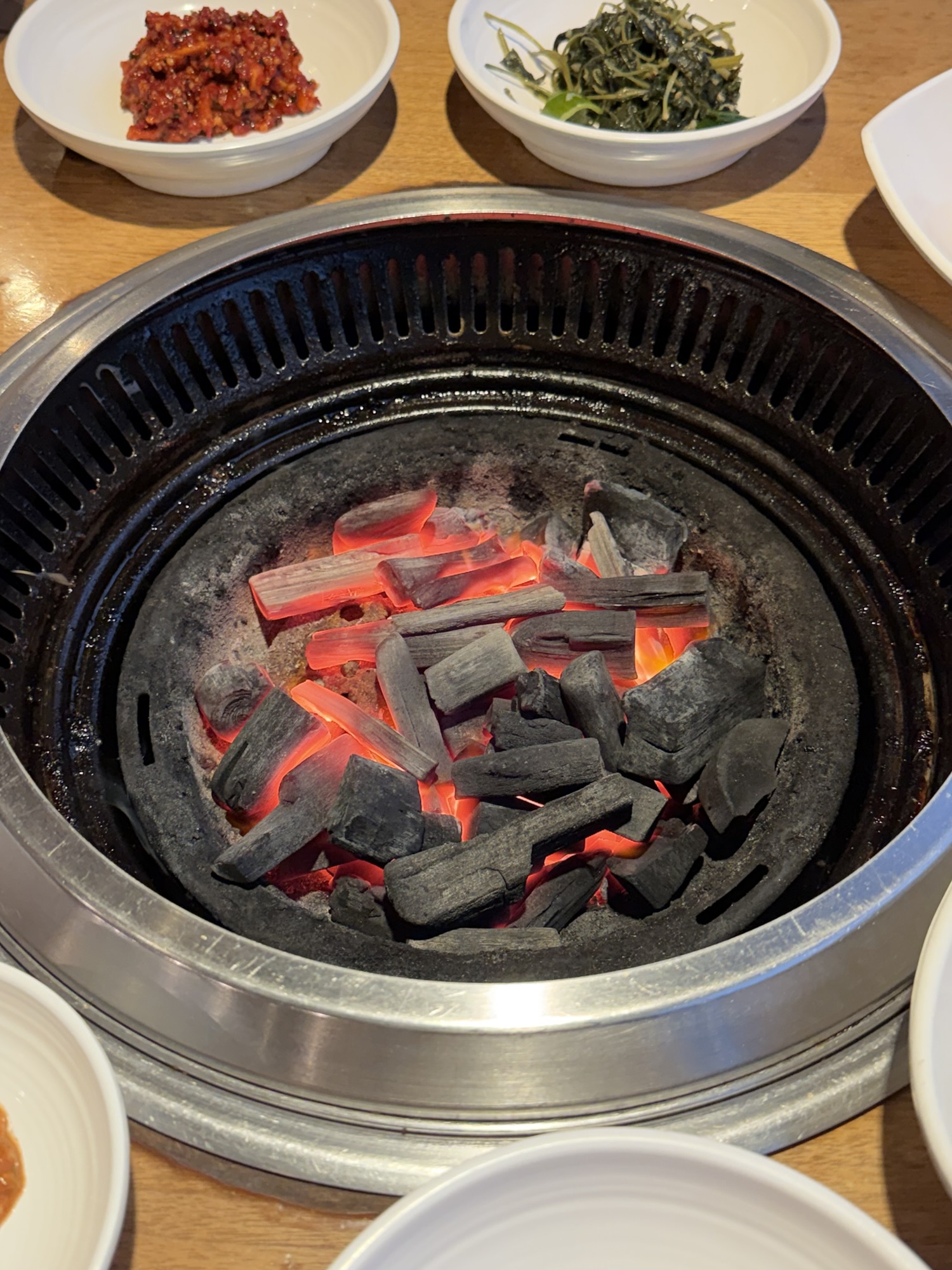 Fresh charcoal loaded into the grill at Songdo Galbi — high-quality charcoal, glowing red and ready
