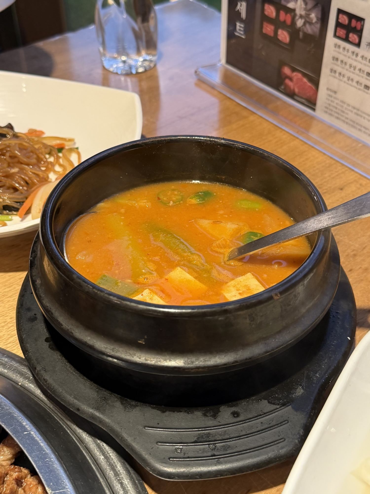 Doenjang jjigae (된장찌개) in a black stone pot at Songdo Galbi — rich, dark broth with tofu, zucchini, and green onion