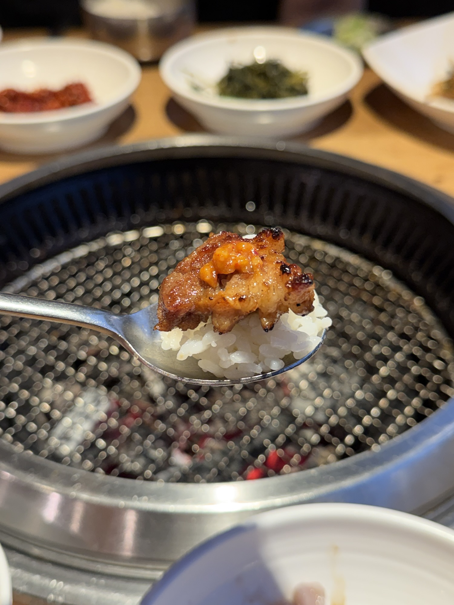 A spoonful of white rice topped with a grilled galbi piece and doenjang paste — the rice-and-galbi combo at Songdo Galbi