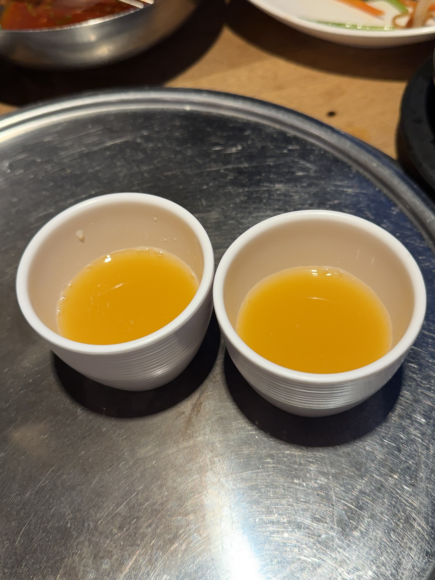 Complimentary danhobak sikhye (단호박 식혜 — sweet pumpkin rice punch) served in small ceramic cups at the end of the meal at Songdo Galbi
