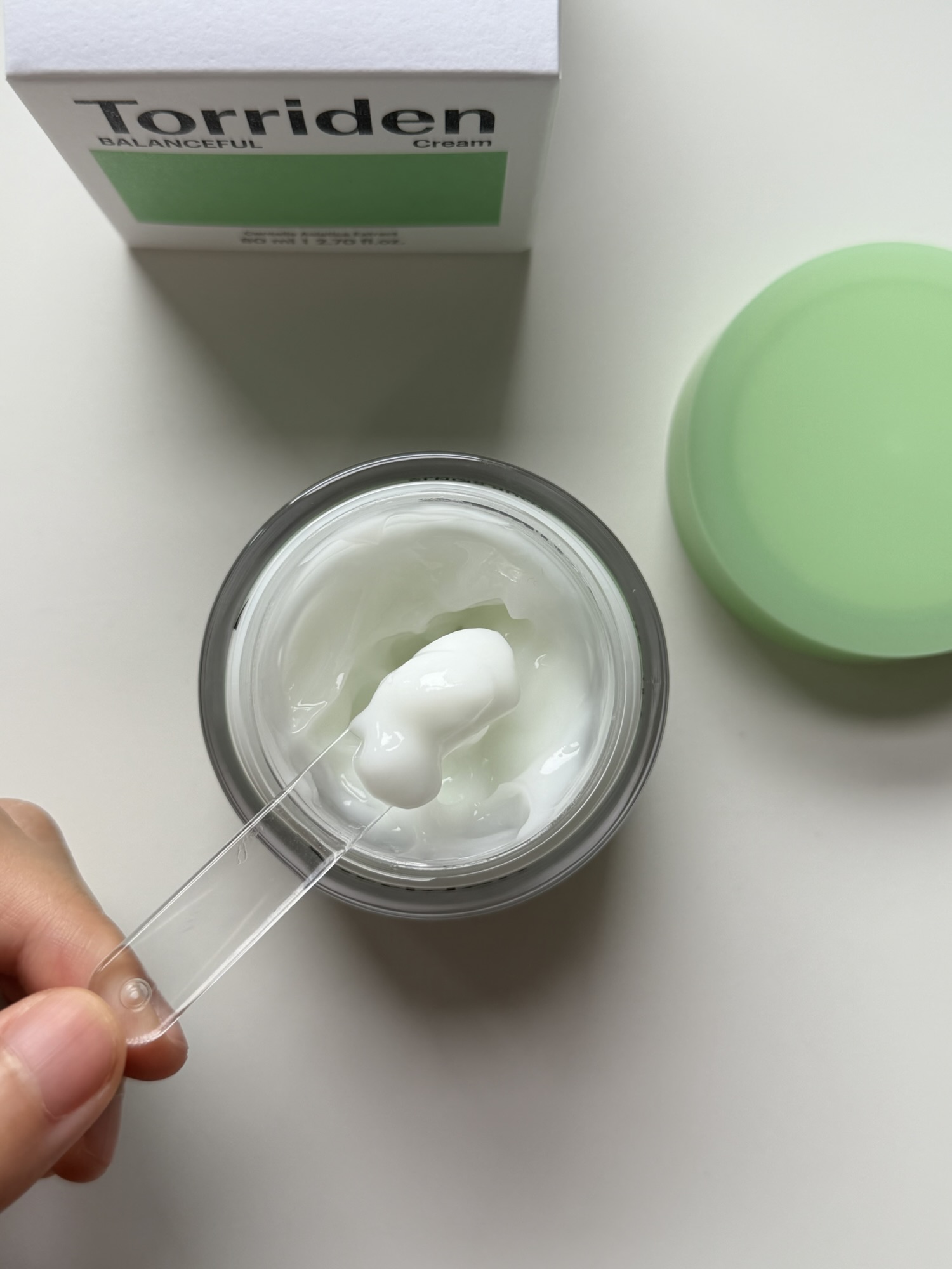 Pudding-like gel texture of Torriden Balanceful Cica Cream lifted on a small spatula before application