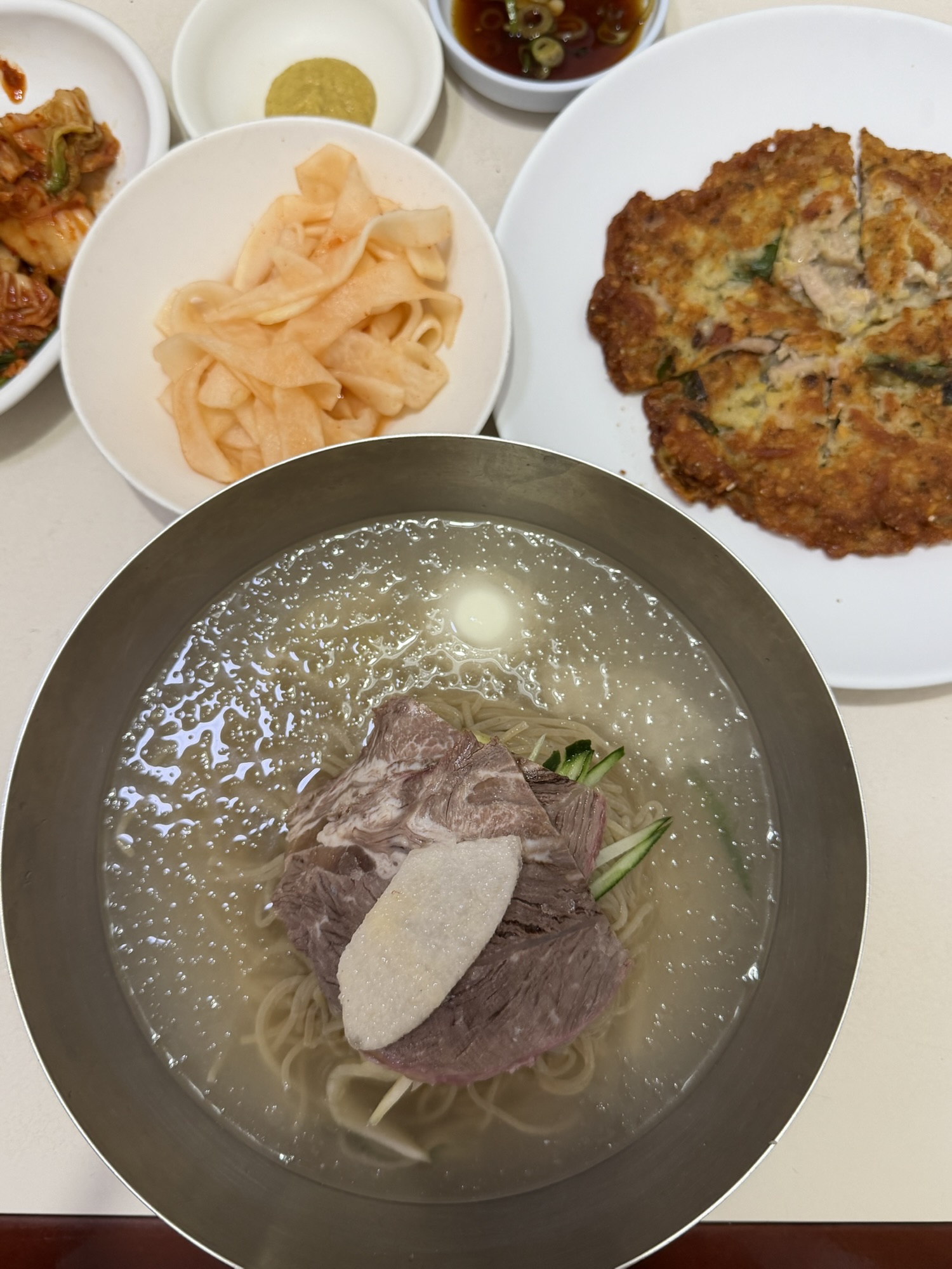 Bowl of Eulmildae Pyongyang naengmyeon with nokdujeon and side dishes