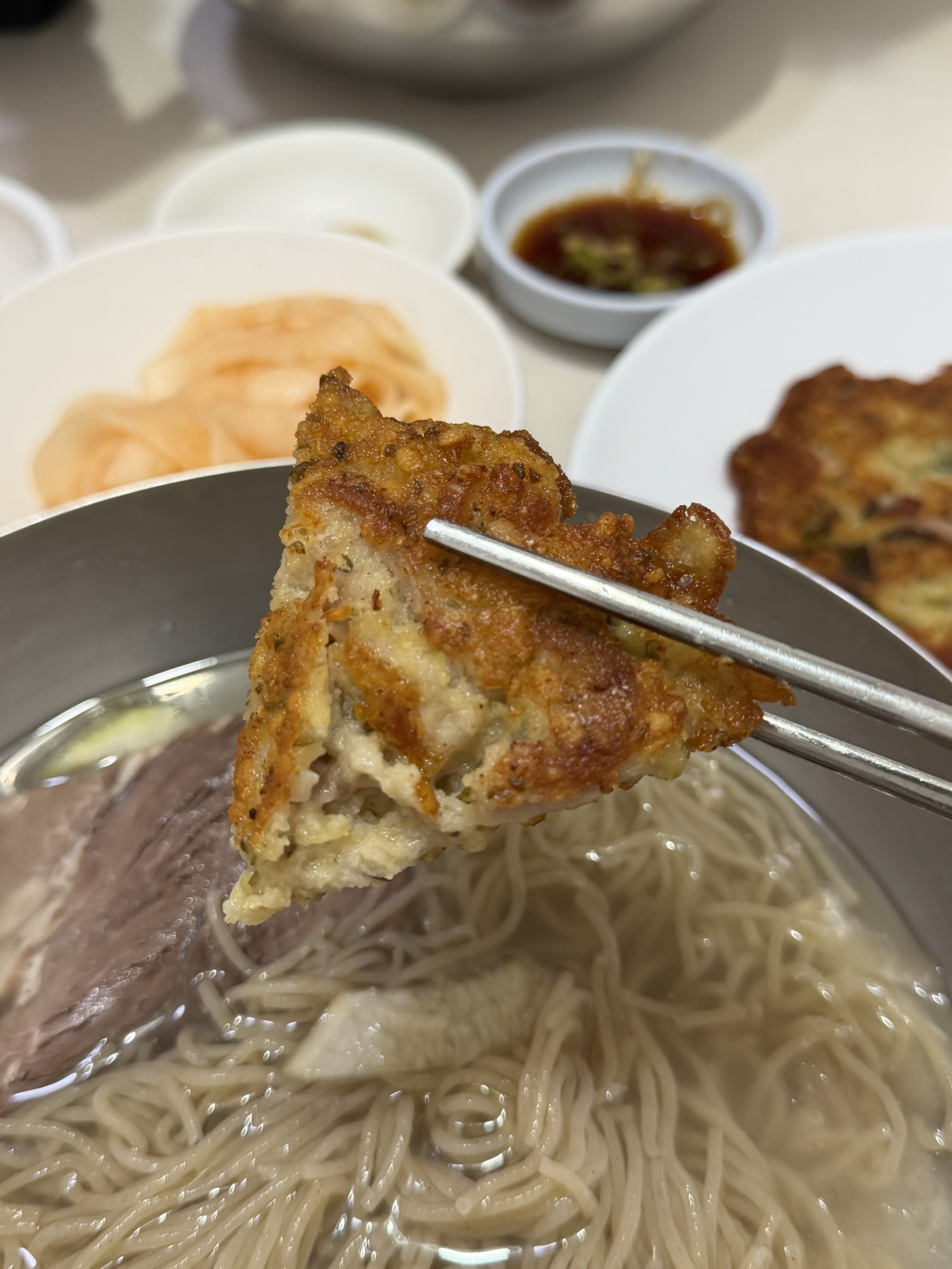 Piece of crispy nokdujeon held with chopsticks at Eulmildae