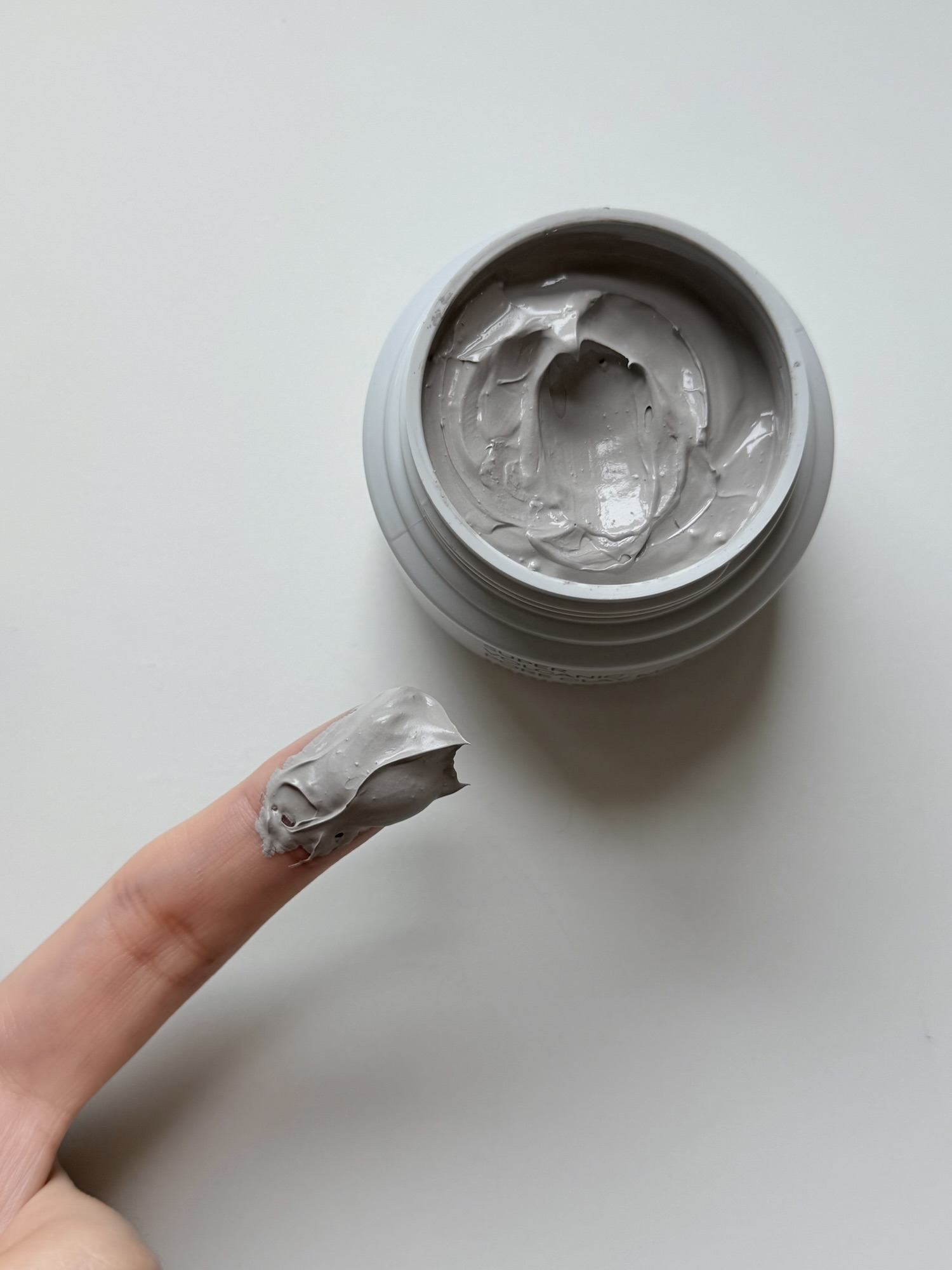 Finger scooping creamy gray Innisfree clay mask from the jar