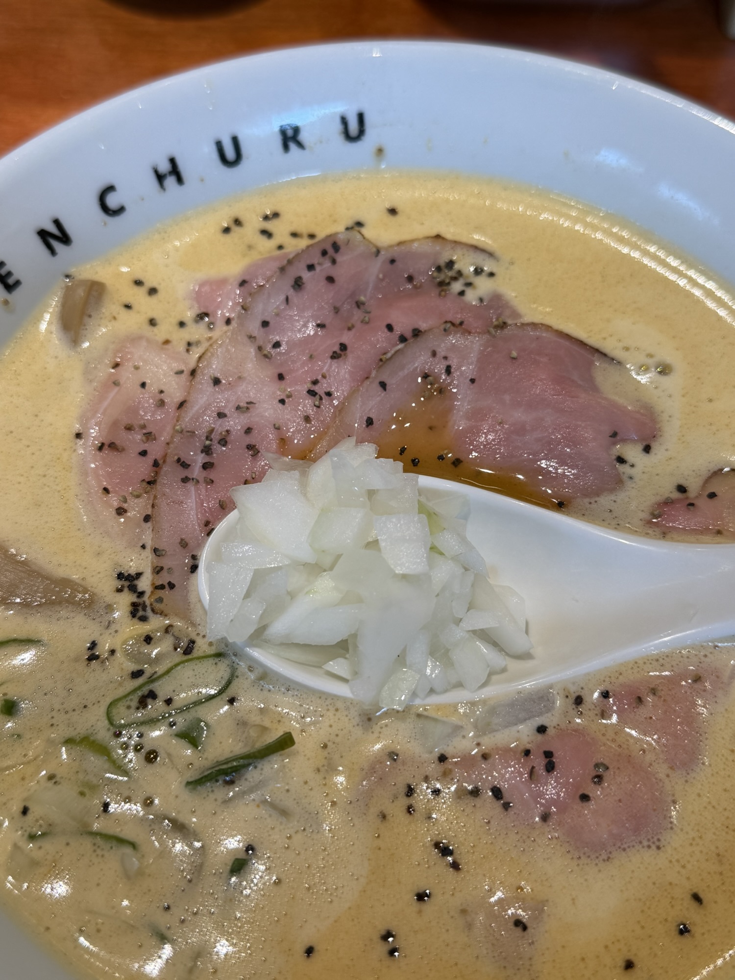 Close-up of spicy paitan ramen with chopped onion and thin chashu at Menchuru Yeouido