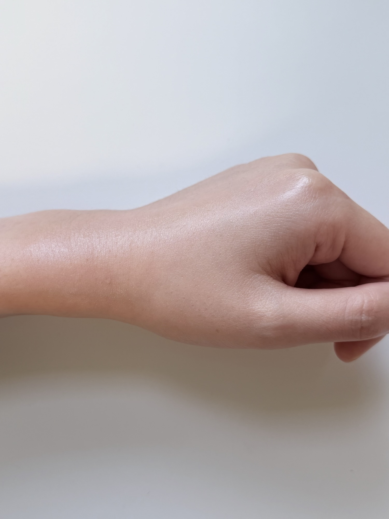 Kopher Curepair Mela Cream after blending on the back of a hand with a slightly dewy finish