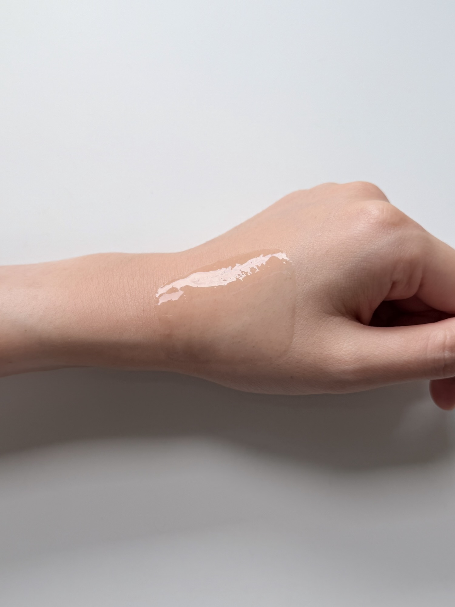 Mediheal Madecassoside serum spread across the back of a hand showing watery texture