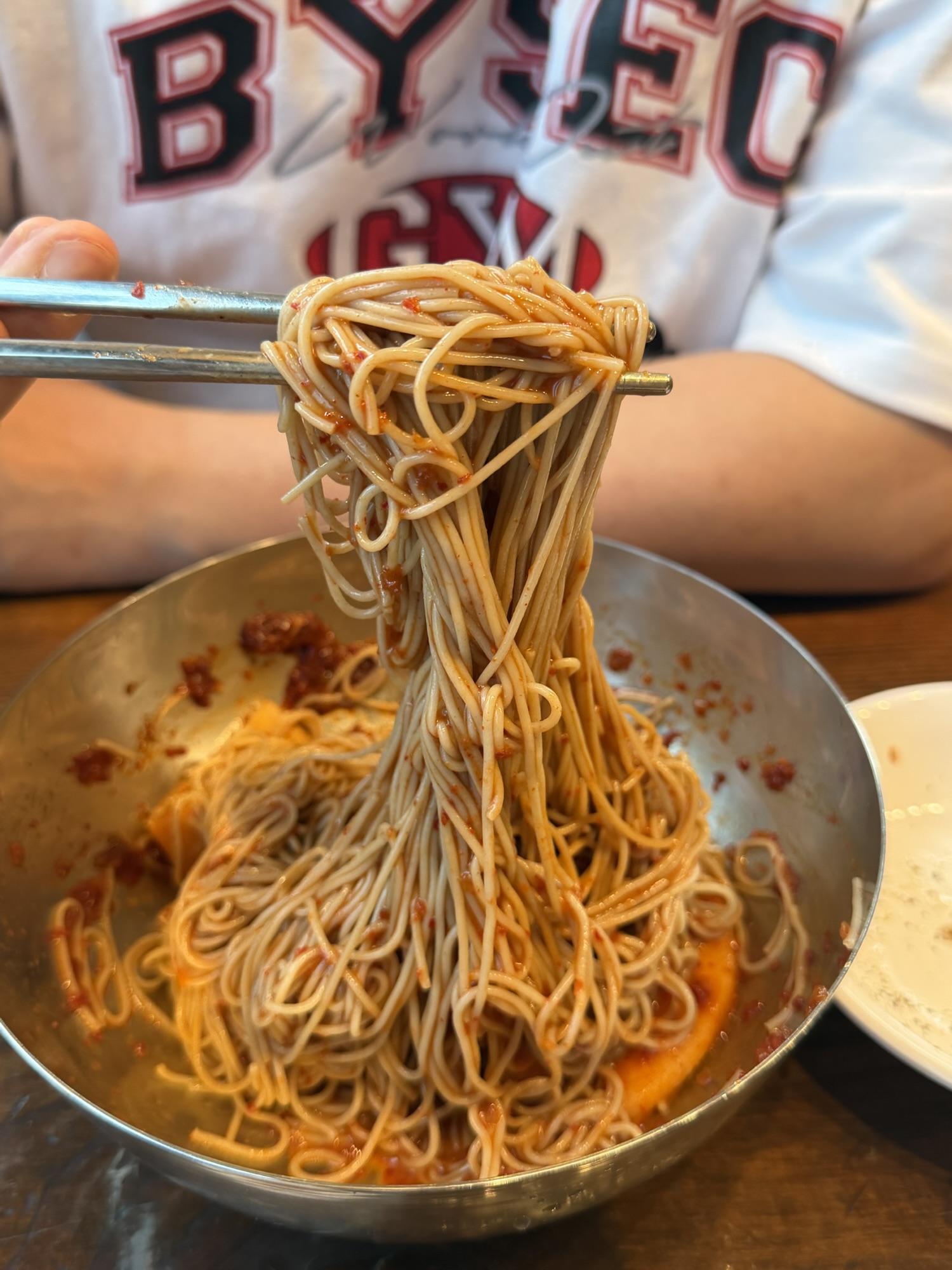 Bibim makguksu noodles lifted with chopsticks