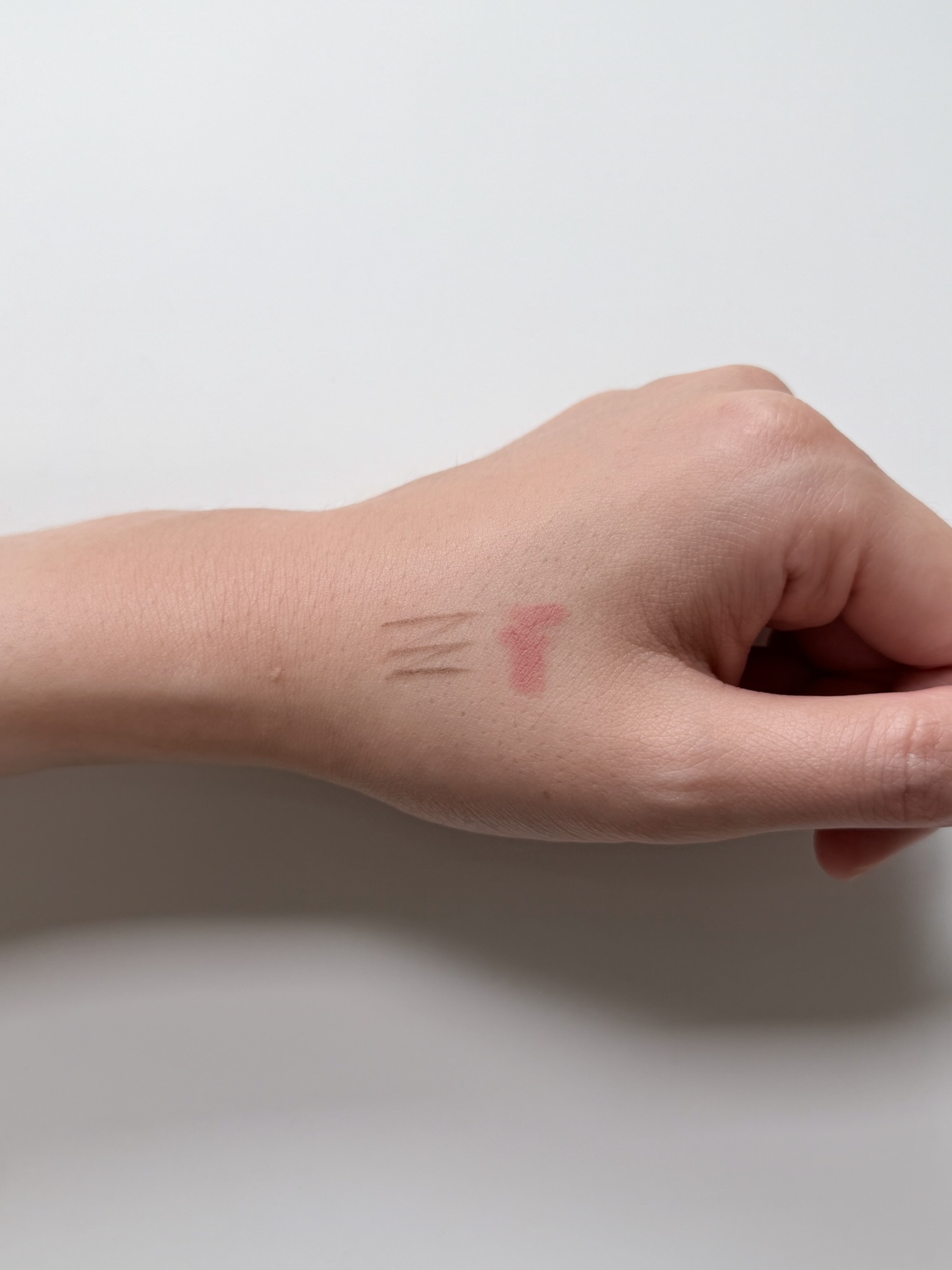 Eyebrow pencil and lip liner marks on the back of a hand for a coverage test