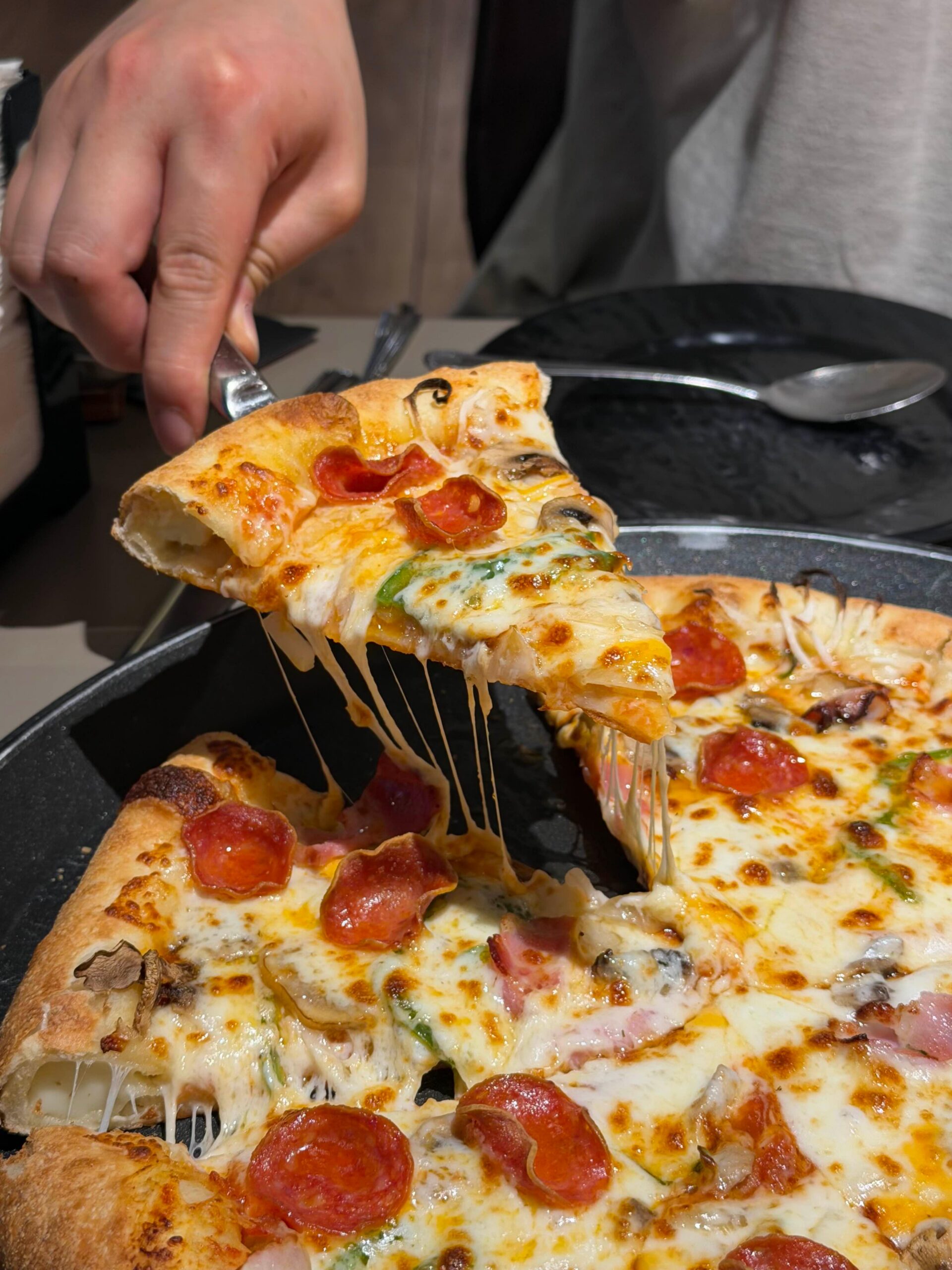 Cheese-crust pizza slice being lifted at Lee Jaemo Pizza in Busan