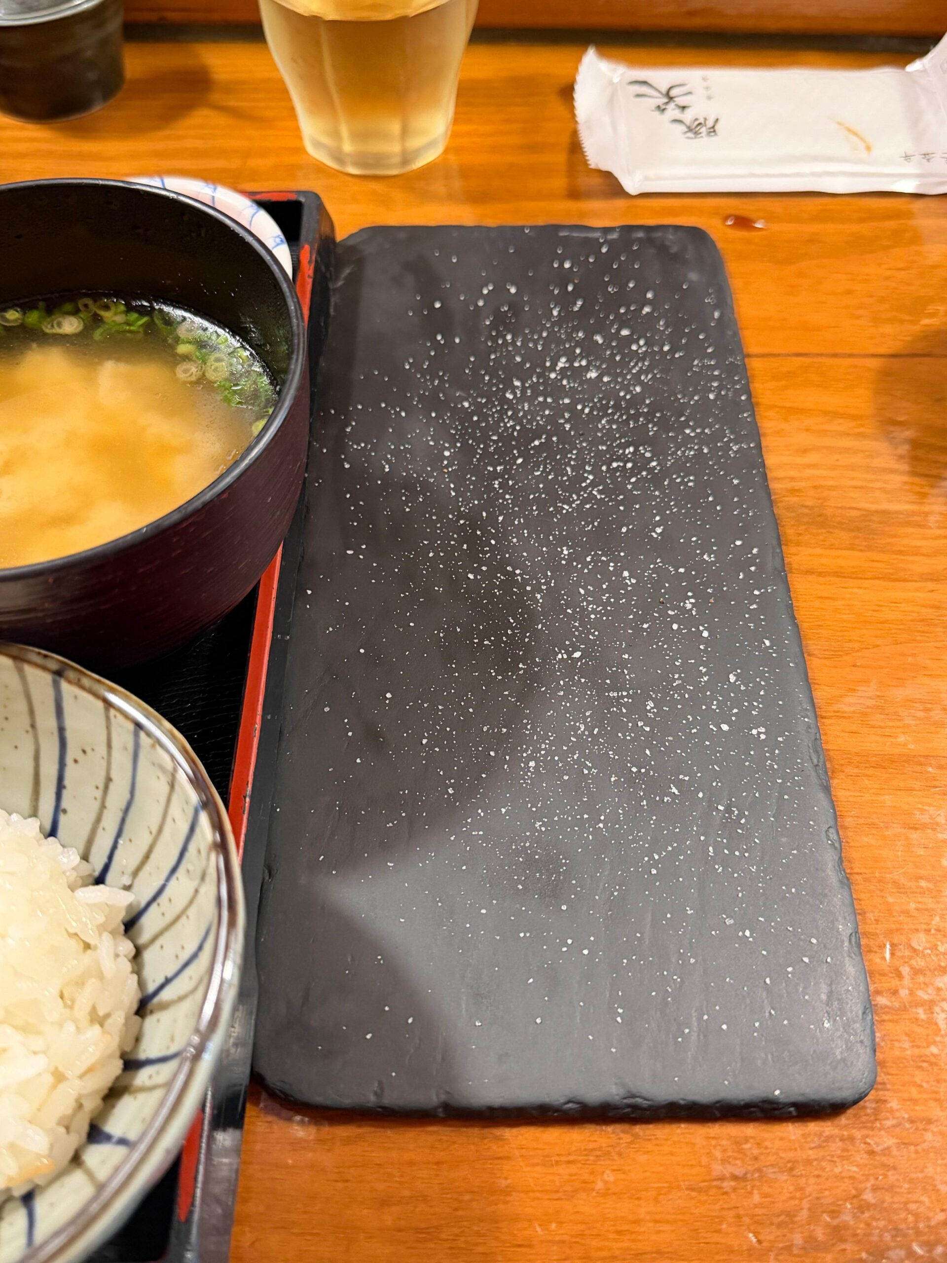 Truffle salt served on a black plate beside rice and miso soup at Tonshou Busan
