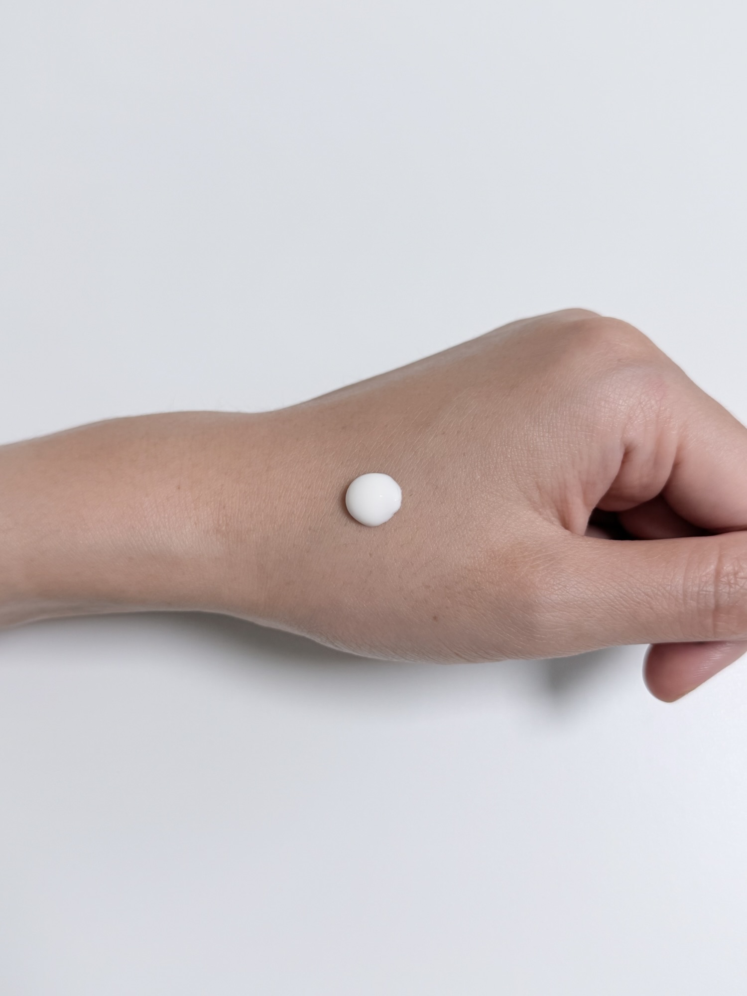 White cream texture of VT PDRN Air Cloud Sunscreen squeezed onto the back of a hand