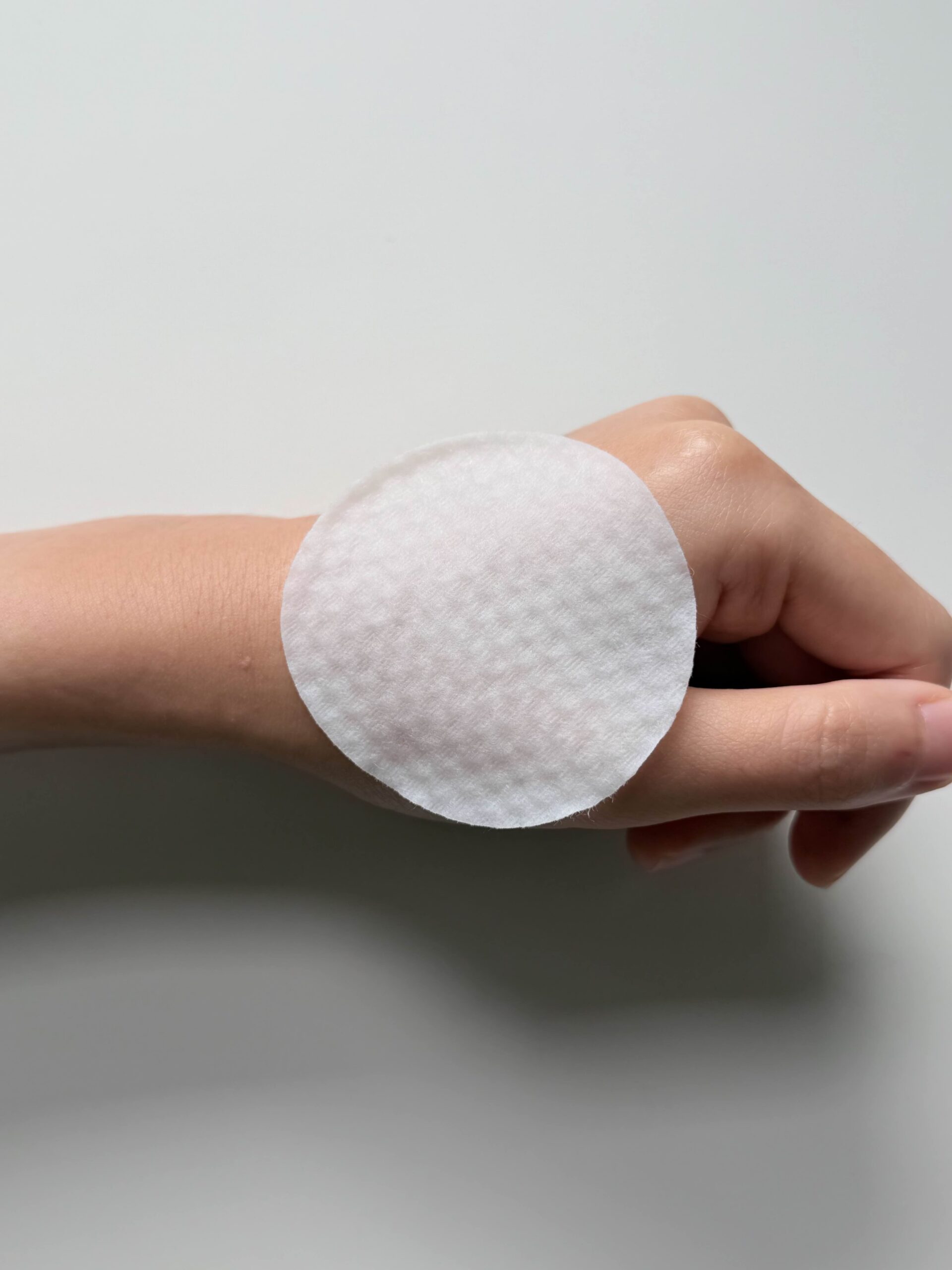 Smooth side of Medicube Zero Pore Pad 2.0 toner pad held between fingers