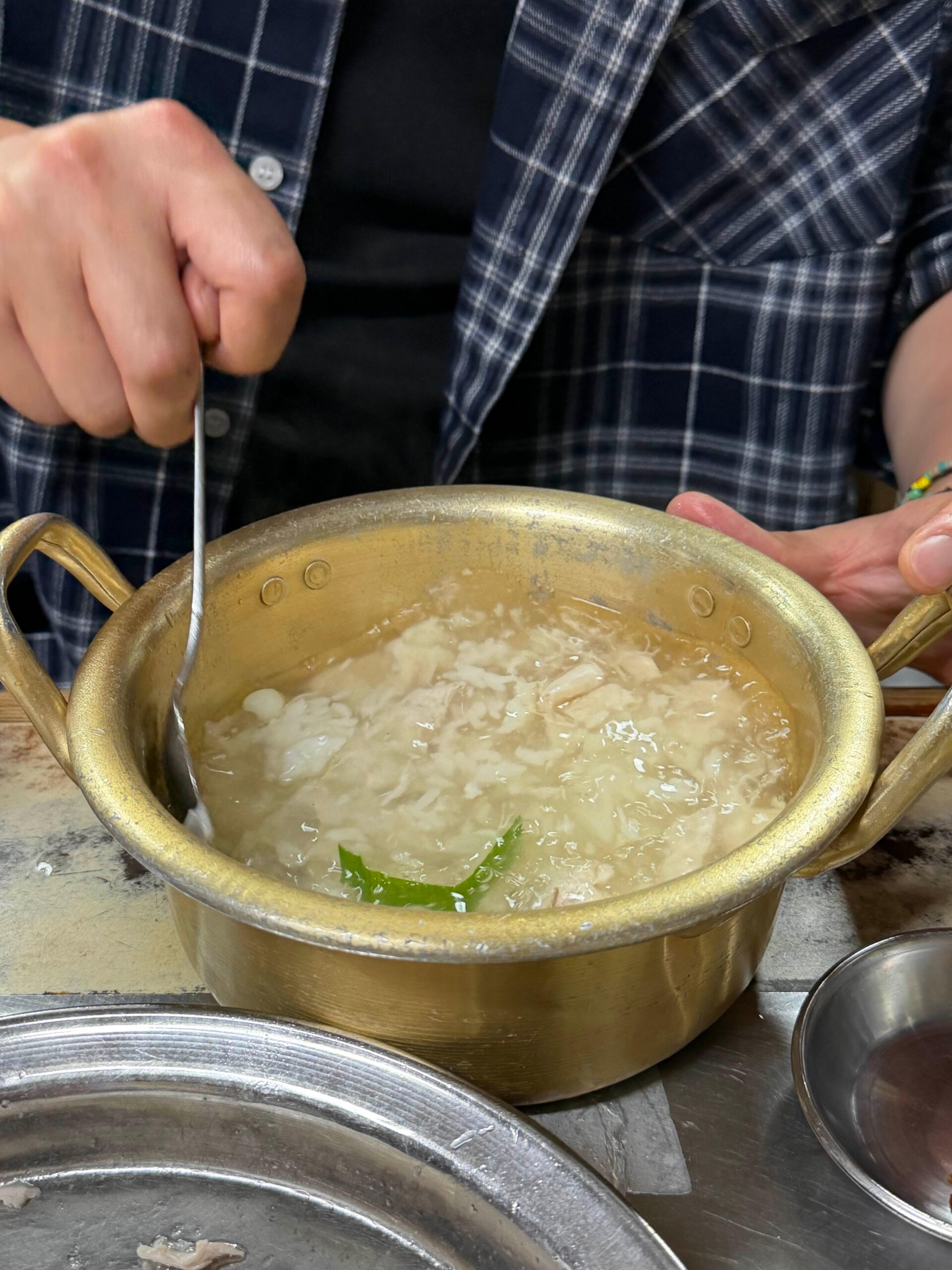 Chicken baeksuk breast meat added to broth and rice at Sarangbang Kalguksu
