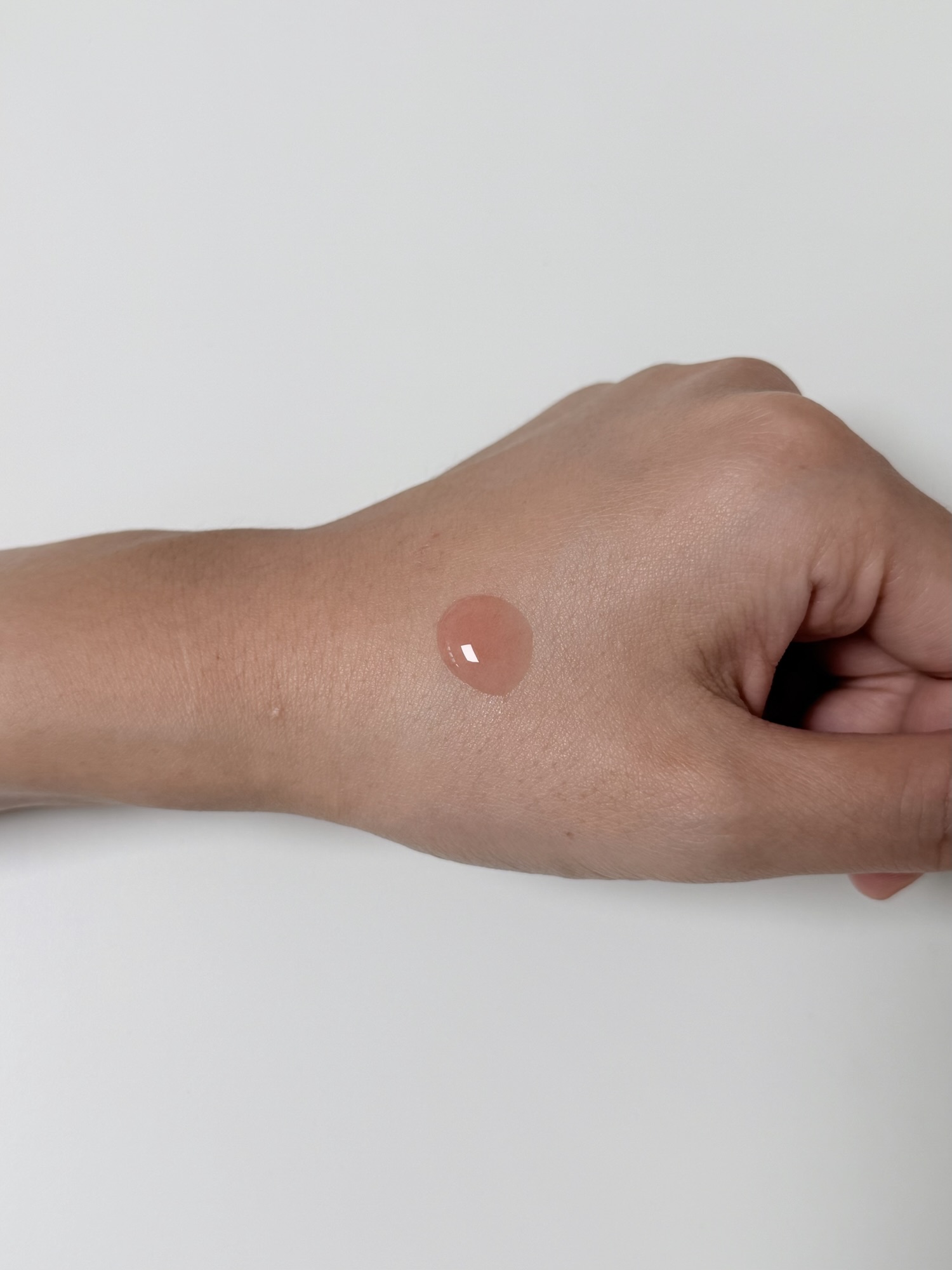 One drop of CNP TXA-PDRN Ampule on the back of a hand