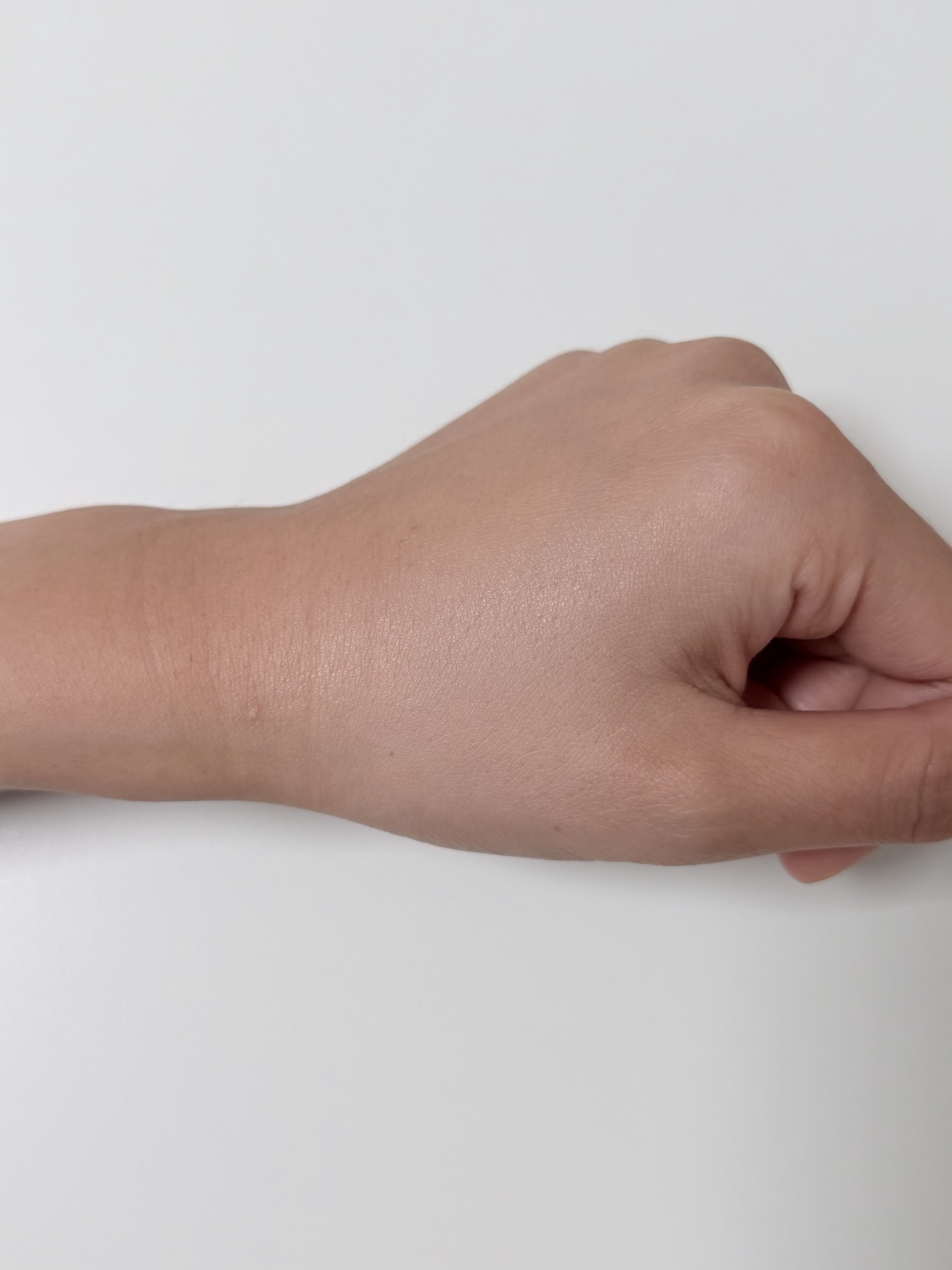 NAMING Layered Fit Cushion blended thinly on the back of a hand