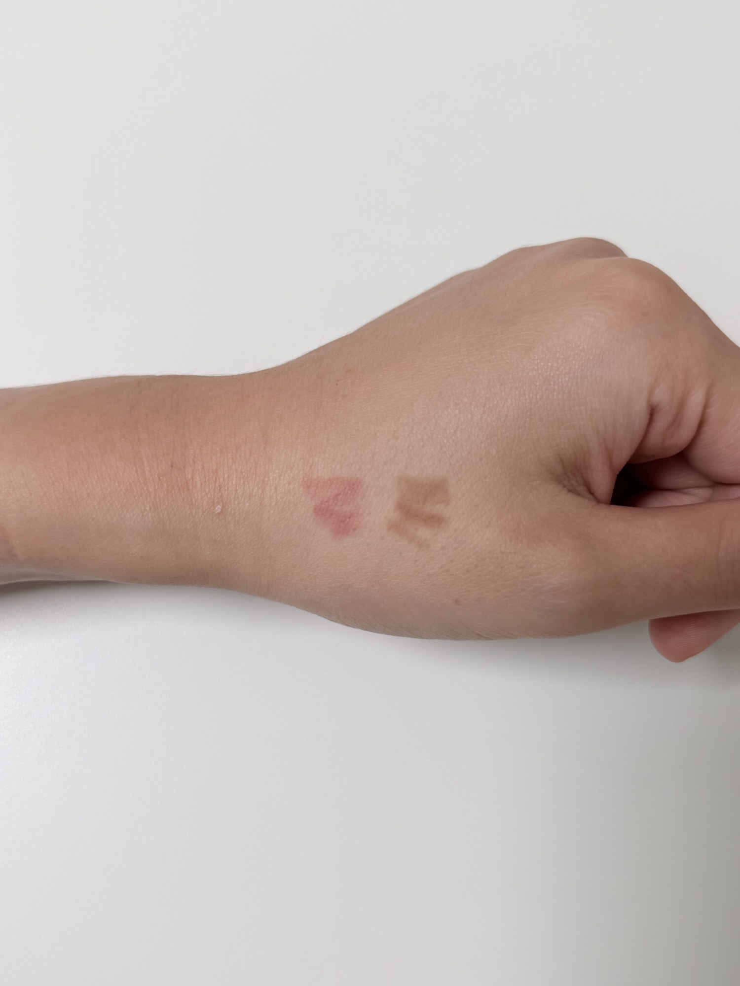 Lip and eyebrow swatches on the back of a hand before cushion coverage test