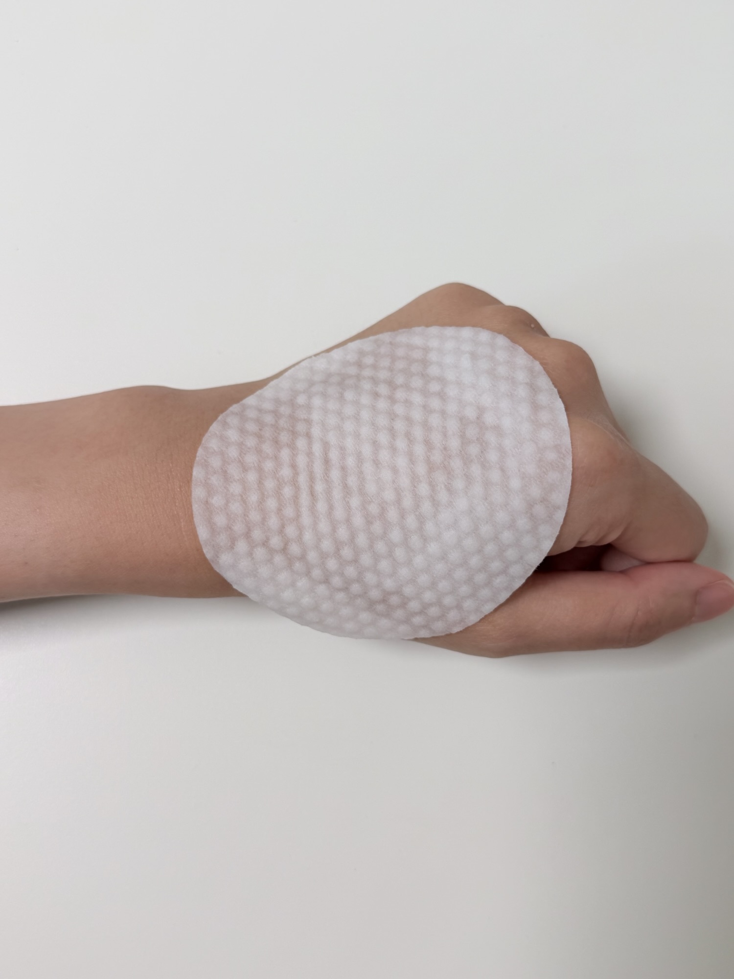 Embossed side of large Needly toner pad on the back of a hand